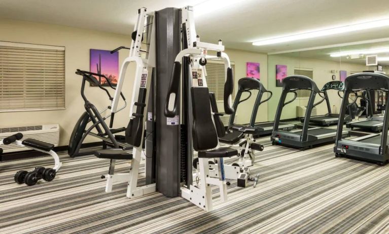 Sonesta Simply Suites Detroit Troy’s fitness center includes free weights, a mirrored wall, and various types of exercise machine.