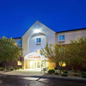 The hotel’s exterior has potted plants and benches by the front door, with trees and bushes nearby.