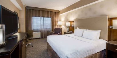 Double bed guest room in Sonesta White Plains Downtown, featuring window, armchair, and TV.