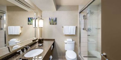 Sonesta White Plains Downtown guest bathroom including shower, lavatory, sink, and mirror.