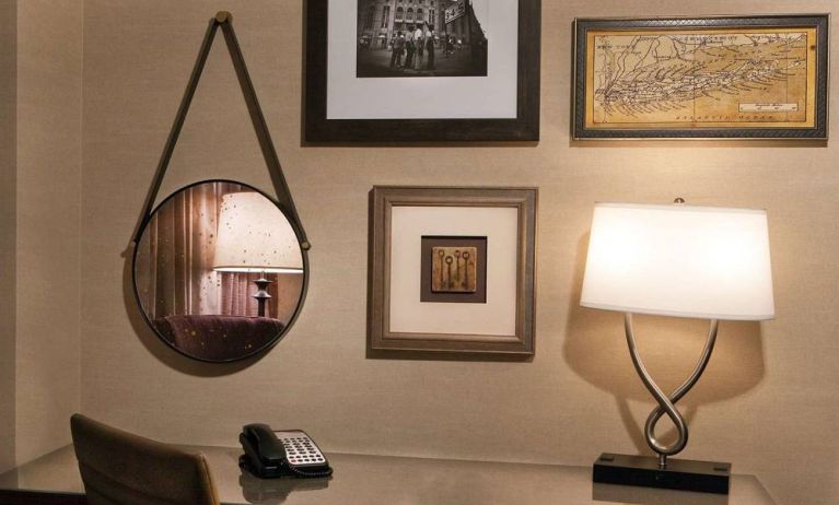 Sonesta White Plains Downtown guest room workspace, including chair, desk, lamp, telephone, and art on the wall.