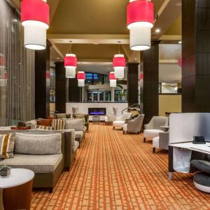 Sonesta White Plains Downtown’s lobby lounge is furnished with sofa and armchair seating, coffee tables, and a fireplace.