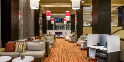 Sonesta White Plains Downtown’s lobby lounge is furnished with sofa and armchair seating, coffee tables, and a fireplace.