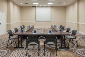 Meeting room in Sonesta White Plains Downtown, with tables arranged in a U-shape, seating for 10, and a projector screen.