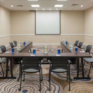 Meeting room in Sonesta White Plains Downtown, with tables arranged in a U-shape, seating for 10, and a projector screen.