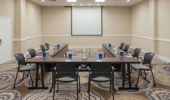 Meeting room in Sonesta White Plains Downtown, with tables arranged in a U-shape, seating for 10, and a projector screen.