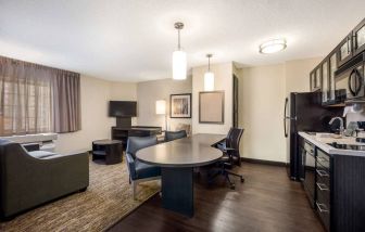 Sonesta Simply Suites Oklahoma City Airport guest room, with a table and three chairs in between the kitchen and living area.