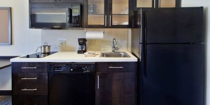 Guest room kitchen in Sonesta Simply Suites Oklahoma City Airport, furnished with microwave, hob, and fridge-freezer.