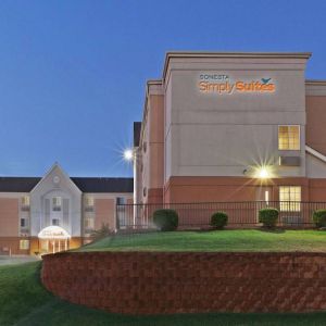 Sonesta Simply Suites Oklahoma City Airport’s exterior has a USA flag, abundant greenery including well-trimmed bushes, and the hotel chain’s name clearly indicated.