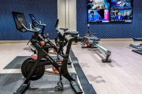 The fitness center in Sonesta Columbus Downtown has an assortment of exercise machines and multiple widescreen TVs on the wall.