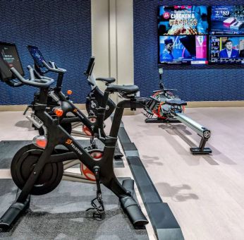 The fitness center in Sonesta Columbus Downtown has an assortment of exercise machines and multiple widescreen TVs on the wall.