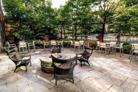 Sonesta Columbus Downtown’s patio features a fire pit that is surrounded by chairs with more tables and chairs nearby.