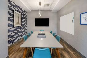 Sonesta Columbus Downtown meeting room, featuring whiteboard and wall-mounted TV, plus a long table and eight chairs.