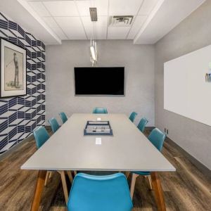 Sonesta Columbus Downtown meeting room, featuring whiteboard and wall-mounted TV, plus a long table and eight chairs.