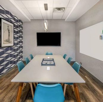 Sonesta Columbus Downtown meeting room, featuring whiteboard and wall-mounted TV, plus a long table and eight chairs.