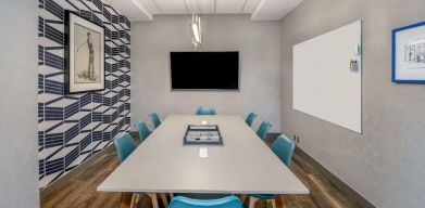 Sonesta Columbus Downtown meeting room, featuring whiteboard and wall-mounted TV, plus a long table and eight chairs.