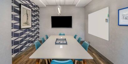 Sonesta Columbus Downtown meeting room, featuring whiteboard and wall-mounted TV, plus a long table and eight chairs.