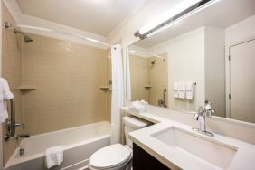 Guest bathroom in Sonesta Simply Suites Austin South, featuring mirror, sink, and lavatory, plus a bath equipped with a shower.