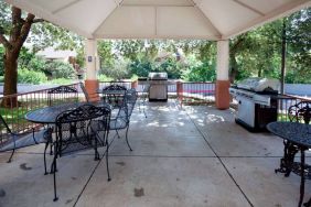 Sonesta Simply Suites Austin The Domain Area’s gazebo has tables and chairs alongside barbecues, and numerous trees nearby.