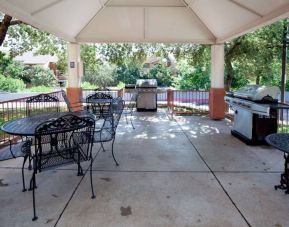 Sonesta Simply Suites Austin The Domain Area’s gazebo has tables and chairs alongside barbecues, and numerous trees nearby.