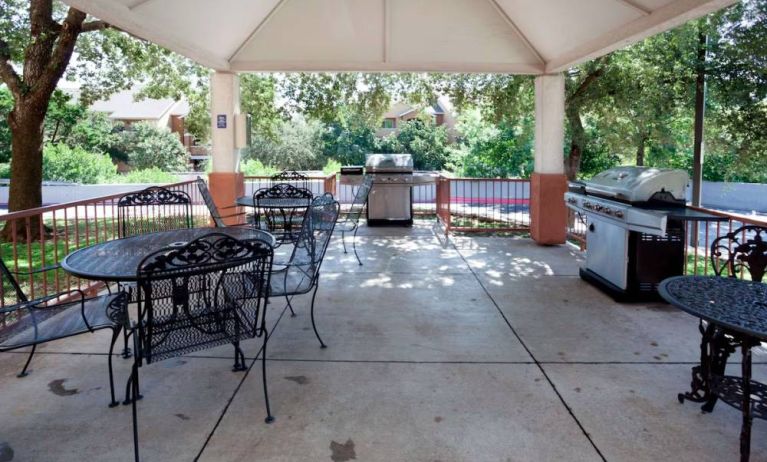 Sonesta Simply Suites Austin The Domain Area’s gazebo has tables and chairs alongside barbecues, and numerous trees nearby.