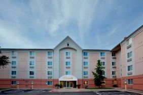 The hotel’s exterior includes disabled parking spaces close to the front door, potted plants, and a tall tree.