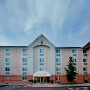 The hotel’s exterior includes disabled parking spaces close to the front door, potted plants, and a tall tree.