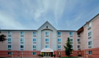 The hotel’s exterior includes disabled parking spaces close to the front door, potted plants, and a tall tree.