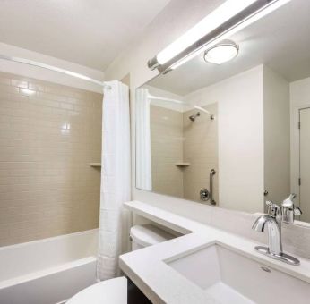 Guest bathroom in Sonesta Simply Suites Houston CityCentre I-10 West, including bath equipped with a shower, mirror, lavatory, and sink.