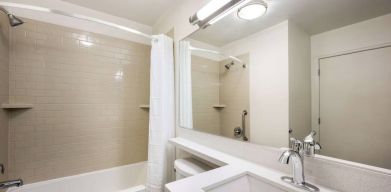 Guest bathroom in Sonesta Simply Suites Houston CityCentre I-10 West, including bath equipped with a shower, mirror, lavatory, and sink.