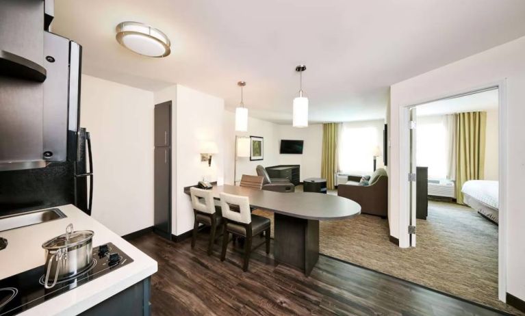 Sonesta Simply Suites Houston CityCentre I-10 West guest room, featuring a kitchen and lounge area, between which is a table and three chairs.