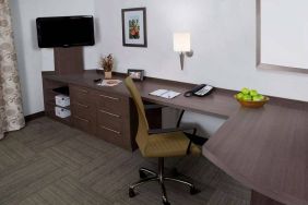 Guest room workspace in Sonesta Simply Suites Houston CityCentre I-10 West, featuring desk, chair, lamp, and telephone.