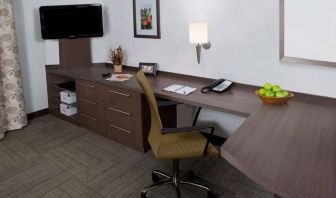 Guest room workspace in Sonesta Simply Suites Houston CityCentre I-10 West, featuring desk, chair, lamp, and telephone.