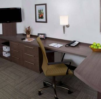 Guest room workspace in Sonesta Simply Suites Houston CityCentre I-10 West, featuring desk, chair, lamp, and telephone.