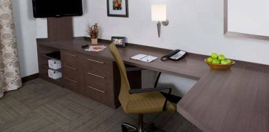 Guest room workspace in Sonesta Simply Suites Houston CityCentre I-10 West, featuring desk, chair, lamp, and telephone.