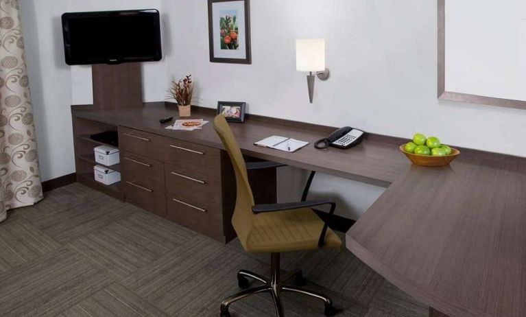 Guest room workspace in Sonesta Simply Suites Houston CityCentre I-10 West, featuring desk, chair, lamp, and telephone.