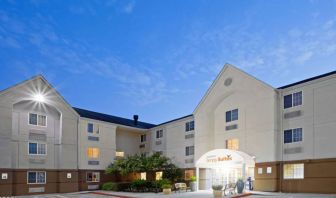 The hotel’s exterior includes parking close to the front door, benches, potted plants, plus bushes, trees, and flowers.