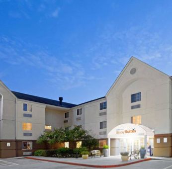 The hotel’s exterior includes parking close to the front door, benches, potted plants, plus bushes, trees, and flowers.