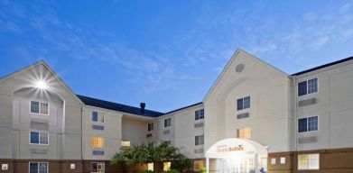 The hotel’s exterior includes parking close to the front door, benches, potted plants, plus bushes, trees, and flowers.