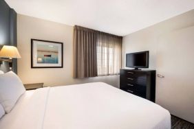 Double bed guest room in Sonesta Simply Suites Plano Frisco, featuring a window, art on the wall, and TV.