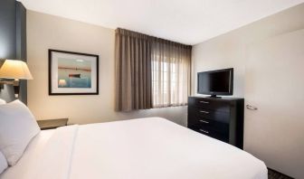 Double bed guest room in Sonesta Simply Suites Plano Frisco, featuring a window, art on the wall, and TV.