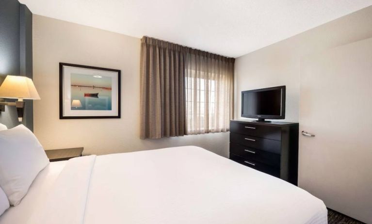 Double bed guest room in Sonesta Simply Suites Plano Frisco, featuring a window, art on the wall, and TV.