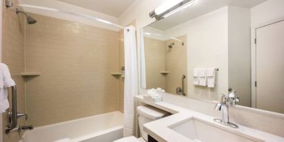 Guest bathroom in Sonesta Simply Suites Plano Frisco, including mirror and sink, lavatory, and bath equipped with a shower.