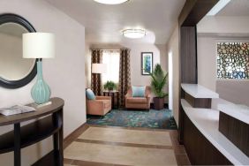 Sonesta Simply Suites Plano Frisco’s lobby features a pair of armchairs, window, coffee table, and potted plants.