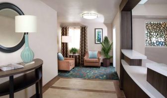 Sonesta Simply Suites Plano Frisco’s lobby features a pair of armchairs, window, coffee table, and potted plants.