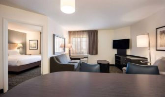 Sonesta Simply Suites Dallas Las Colinas double bed guest room, including sofa, window, and TV.