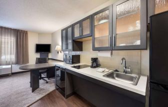 Sonesta Simply Suites Dallas Las Colinas guest room kitchen, fitted with fridge-freezer, hob, sink, and microwave.