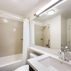 Guest bathroom in Sonesta Simply Suites Dallas Las Colinas, featuring bath with a shower, mirror, sink, and lavatory.