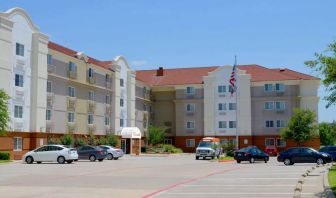 The hotel’s exterior has ample parking for guests, a US flag fluttering on a flagpole, and abundant greenery.