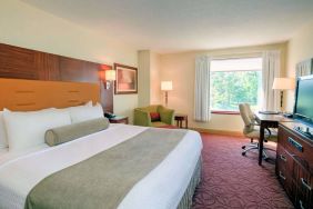 Double bed guest room in Sonesta Milwaukee West Wauwatosa, featuring armchair, window, and television.